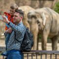 Visitors taking selfies with an elephant in a zoo