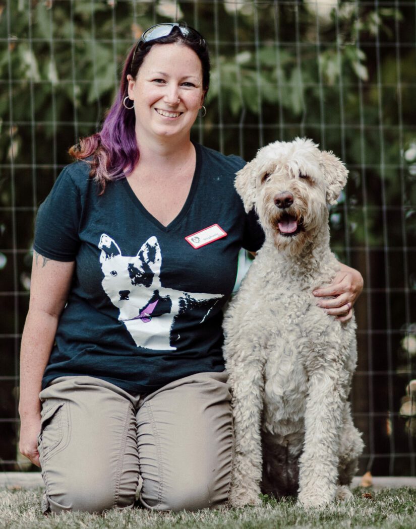 Female dog trainer kneeling beside dog.