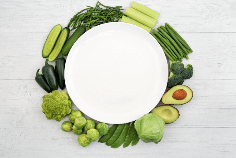 Green vegetables surrounding white plate.