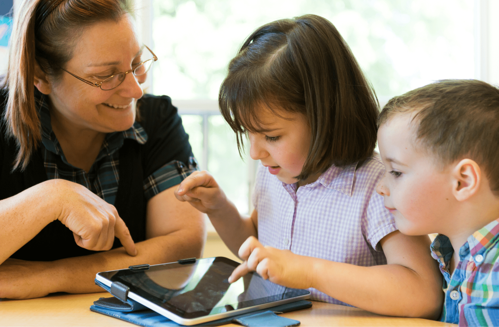 Teacher with two young students using a tablet