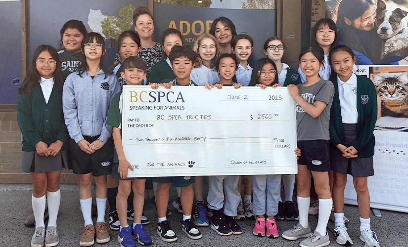 A group of happy middle school students stand outside a BC SPCA Community Animal Centre, proudly displaying a giant cheque noting how much they raised for vulnerable animals during their school-led event.